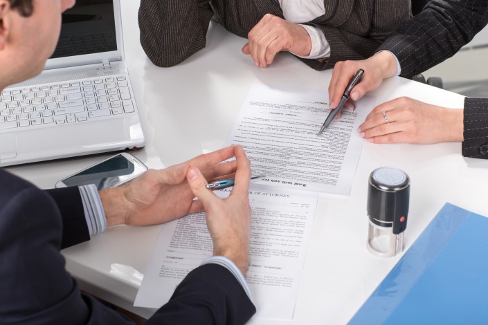 hands of three people, signing documents